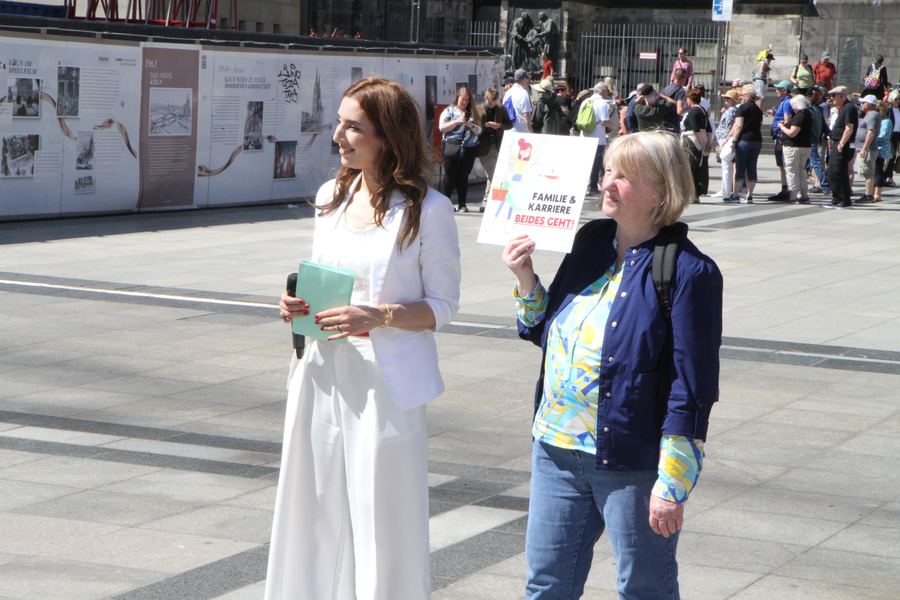 Anissa Saysay moderiert – Teilnehmerin mit Schild „Familie und Karriere – beides geht“